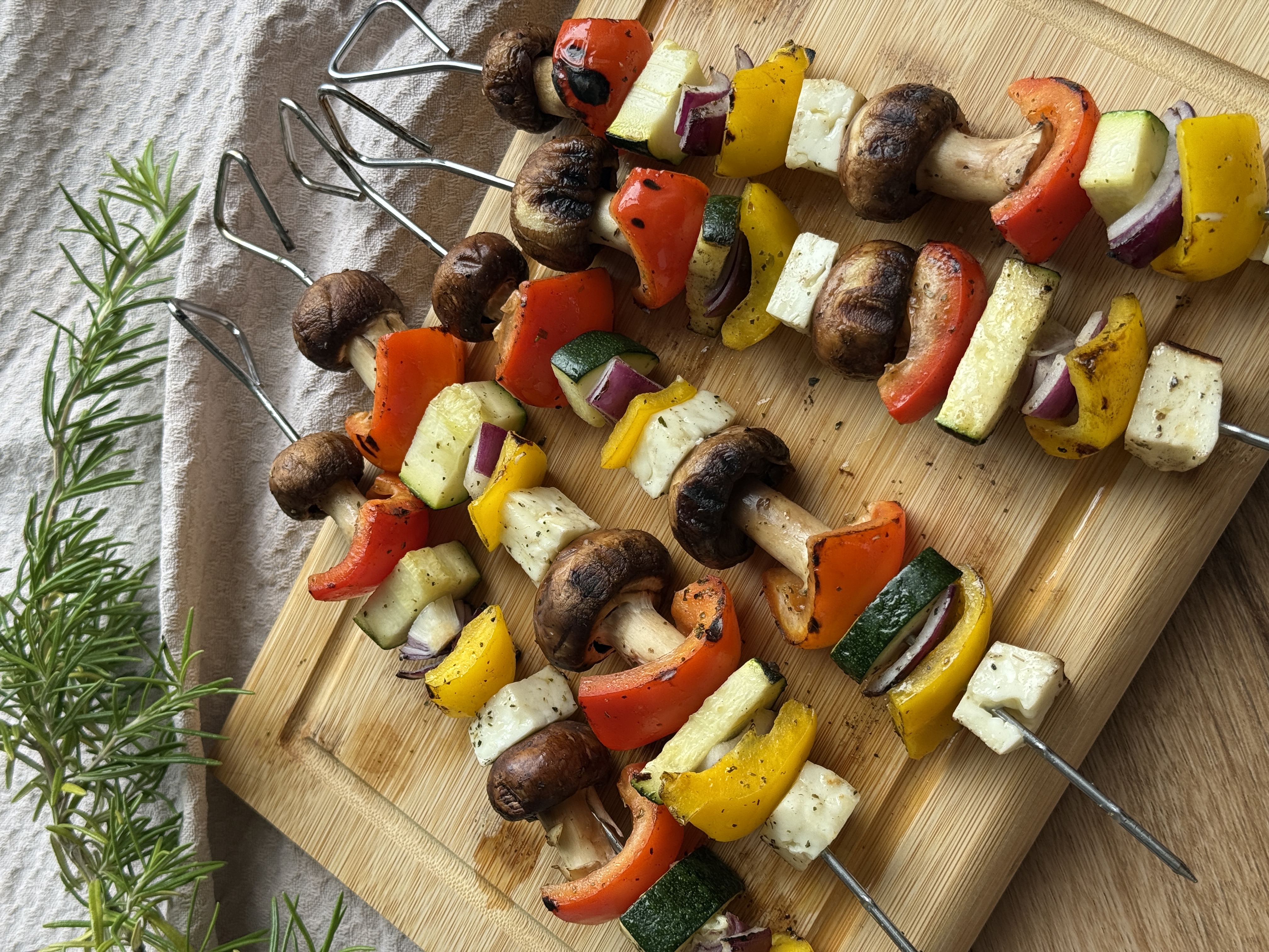Halloumi-Gemüse-Spieße mit Champignons, Zucchini, Paprika und roter Zwiebel auf einem Teller.