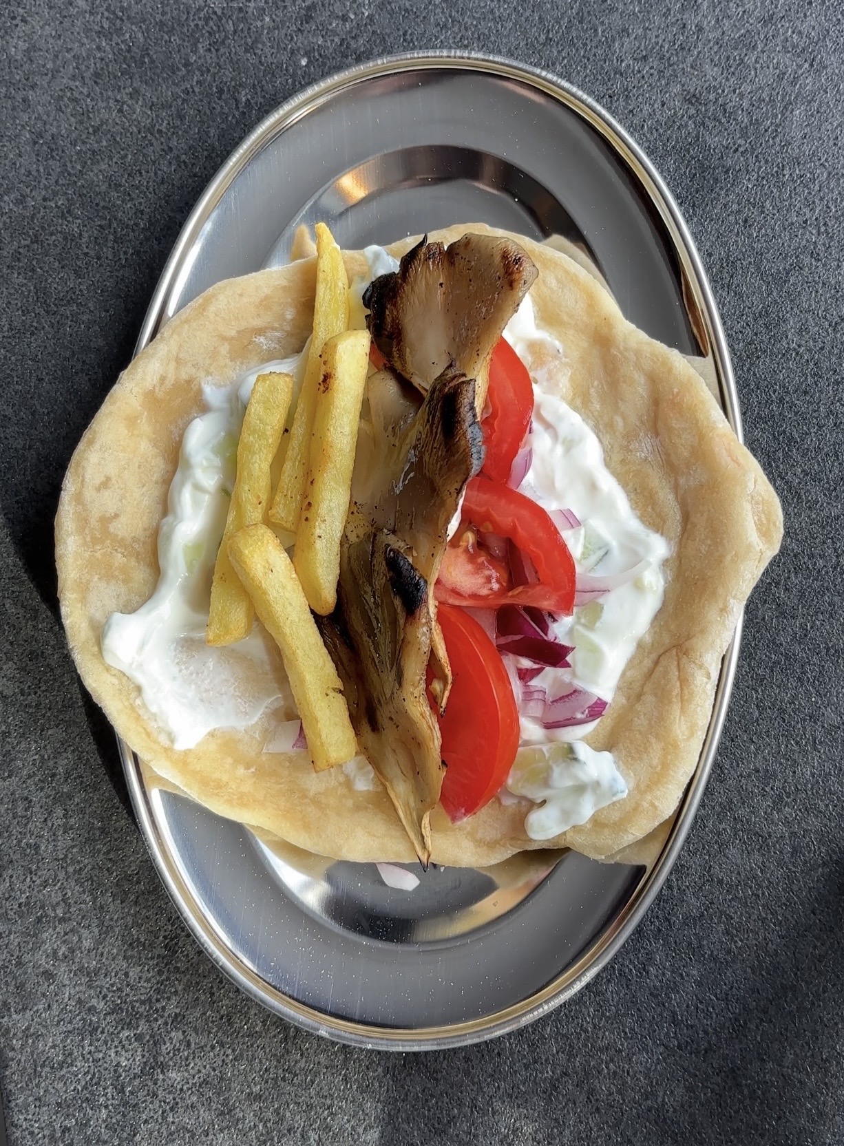 Gefülltes Pita-Brot mit gebratenen Austernpilzen, Pommes, Tomaten und Tzatziki.