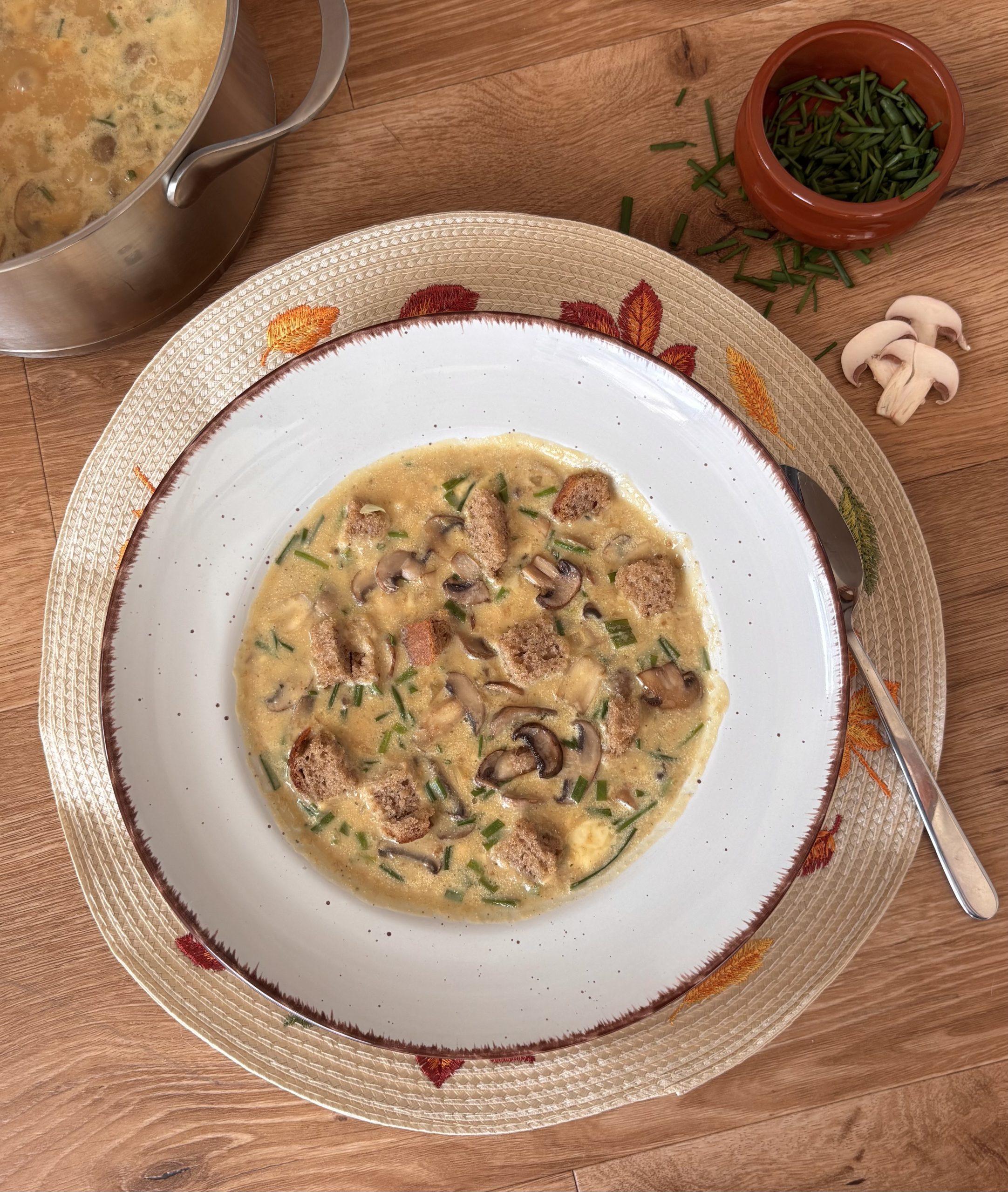 Brotsuppe mit gebratenen Champignons, Brotwürfeln und Schnittlauch in einer Schale