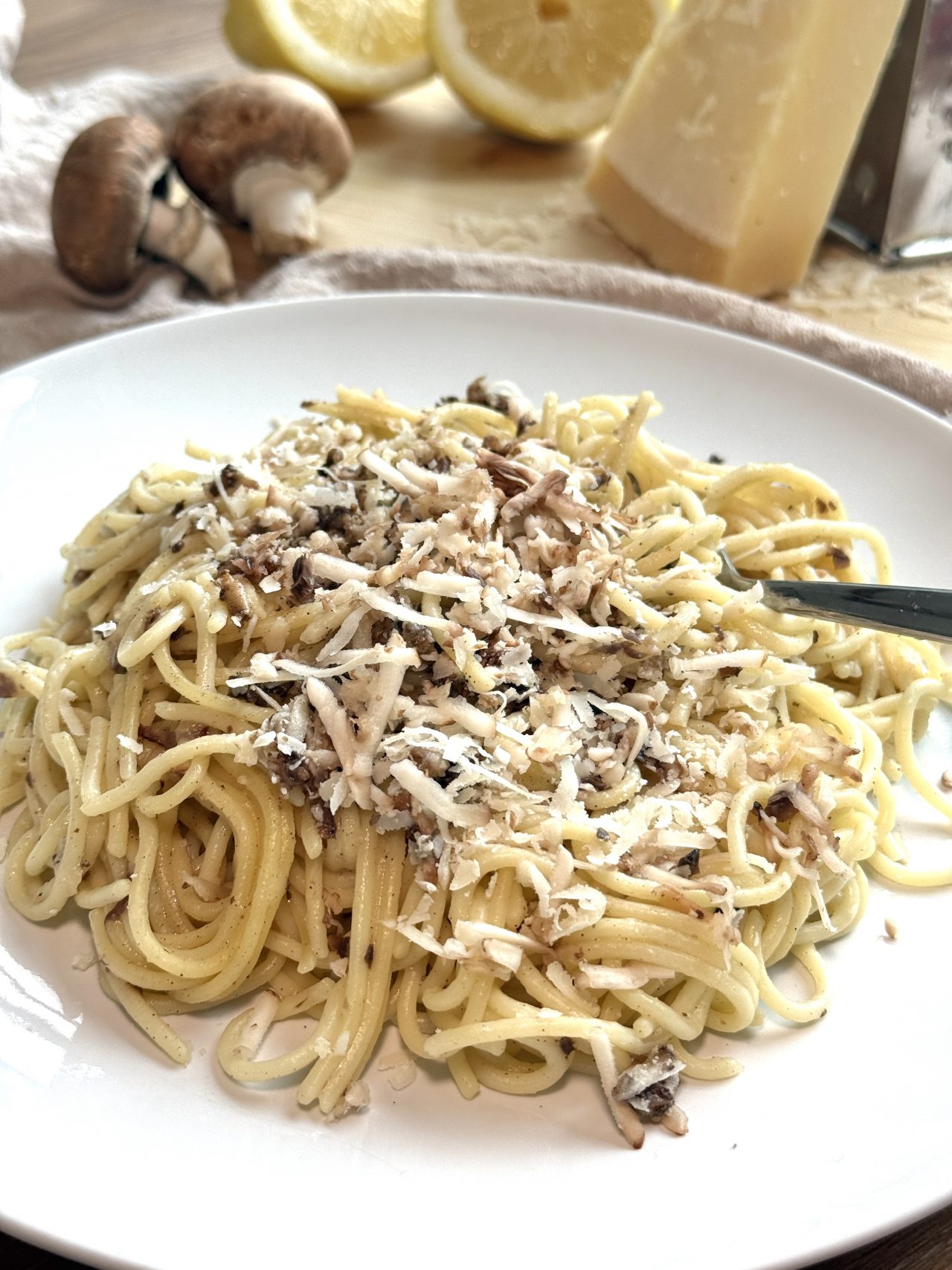 Cacio e Pepe mit Champignons, Pecorino, schwarzem Pfeffer und frisch geriebenen Pilzen auf Spaghetti.