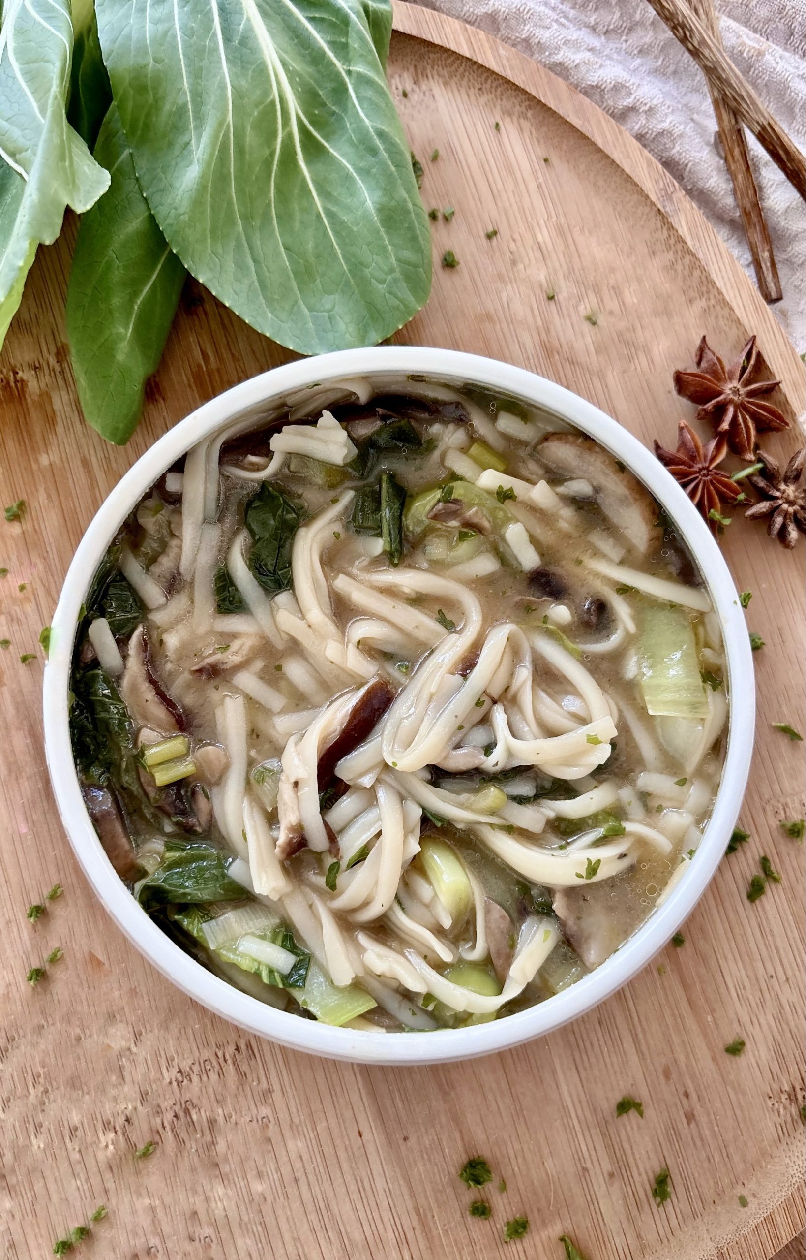 Pho-Suppe mit Shiitake, Champignons, Reisnudeln, Pak Choi und frischen Kräutern in einer Schüssel serviert.