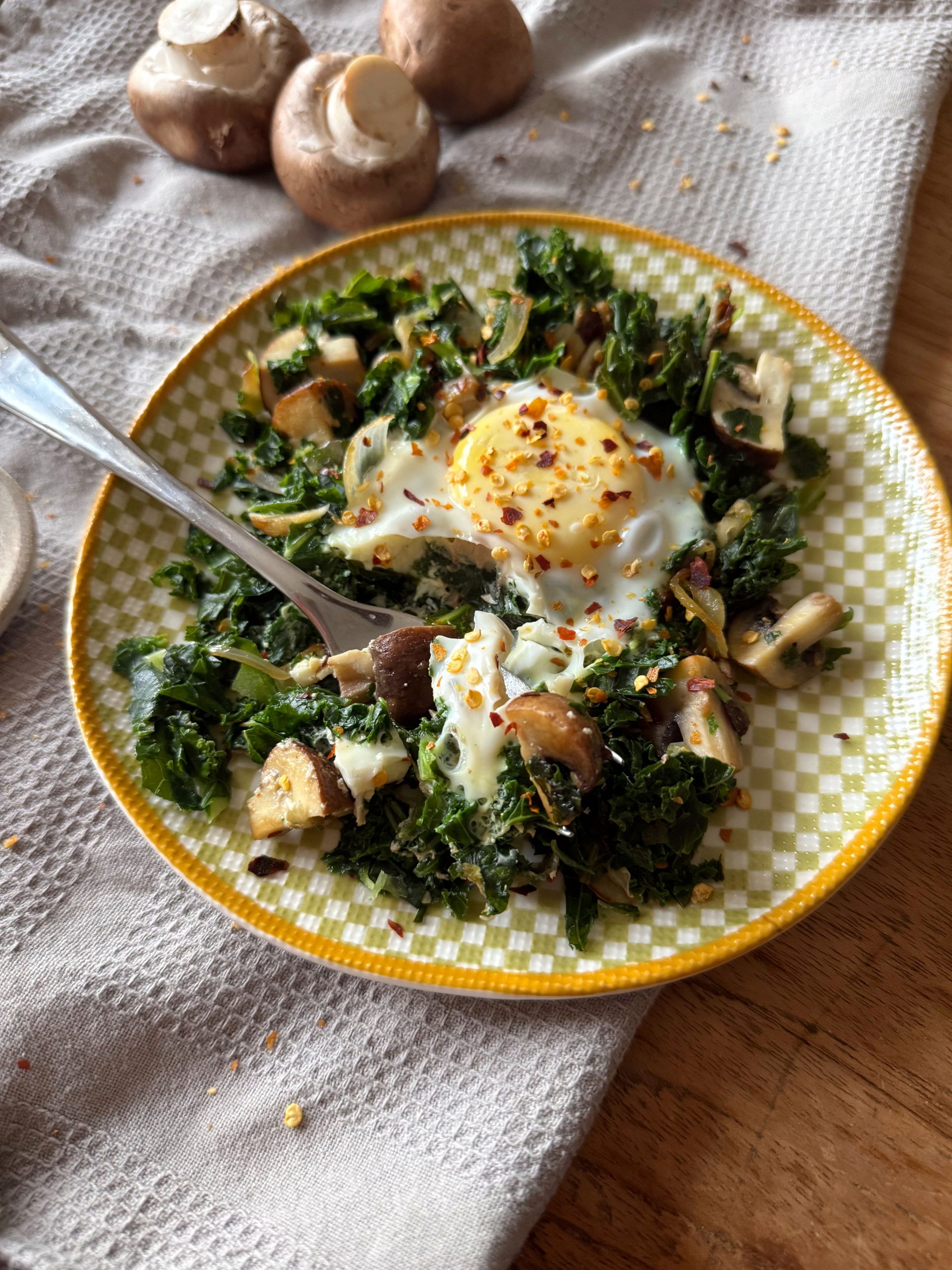 Grünkohl-Shakshuka mit Champignons und Ei, serviert direkt aus der Pfanne.