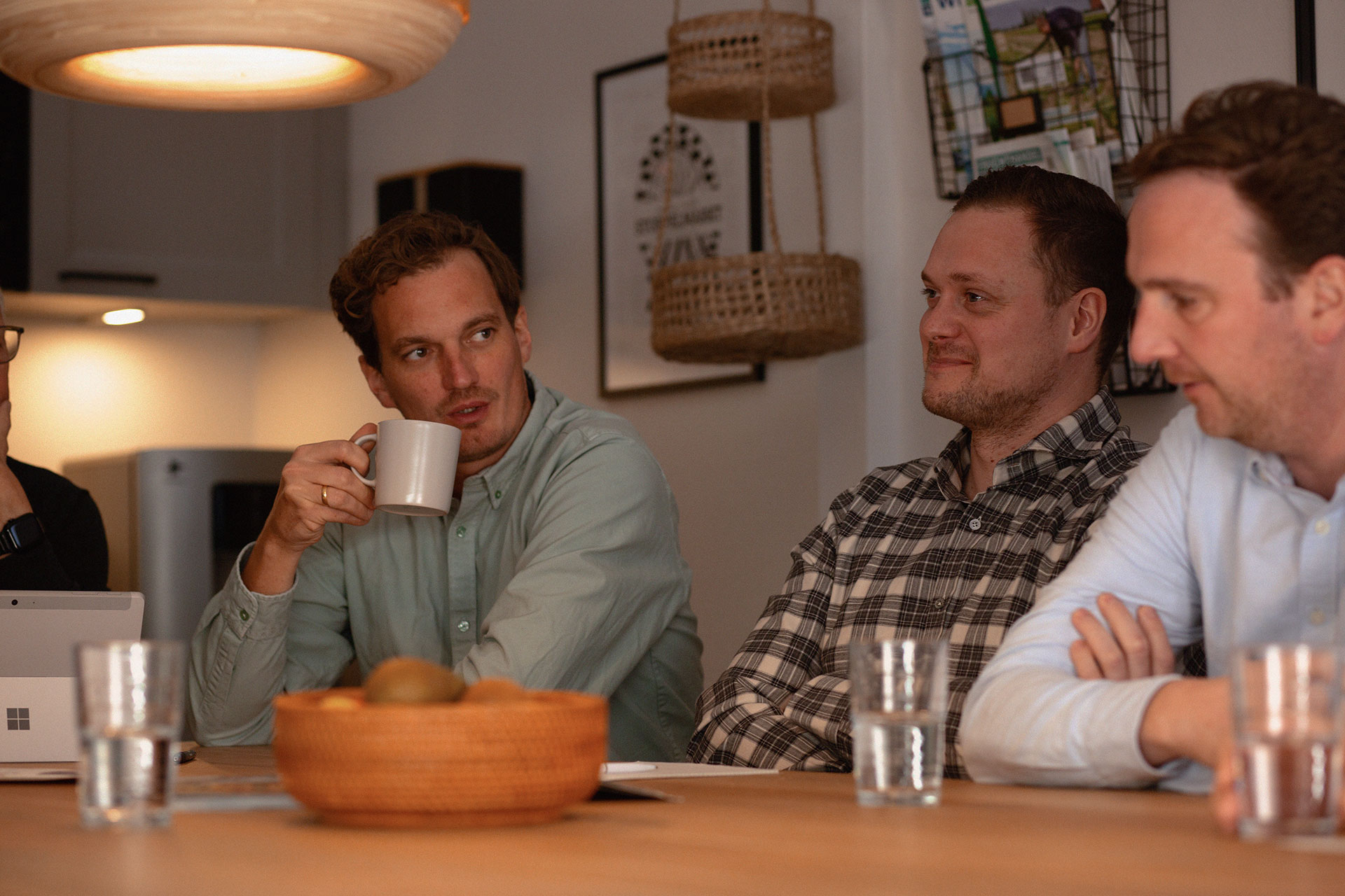 Drei Mitarbeiter unterhalten sich bei Tisch bei der Speisepilzezucht Mjko